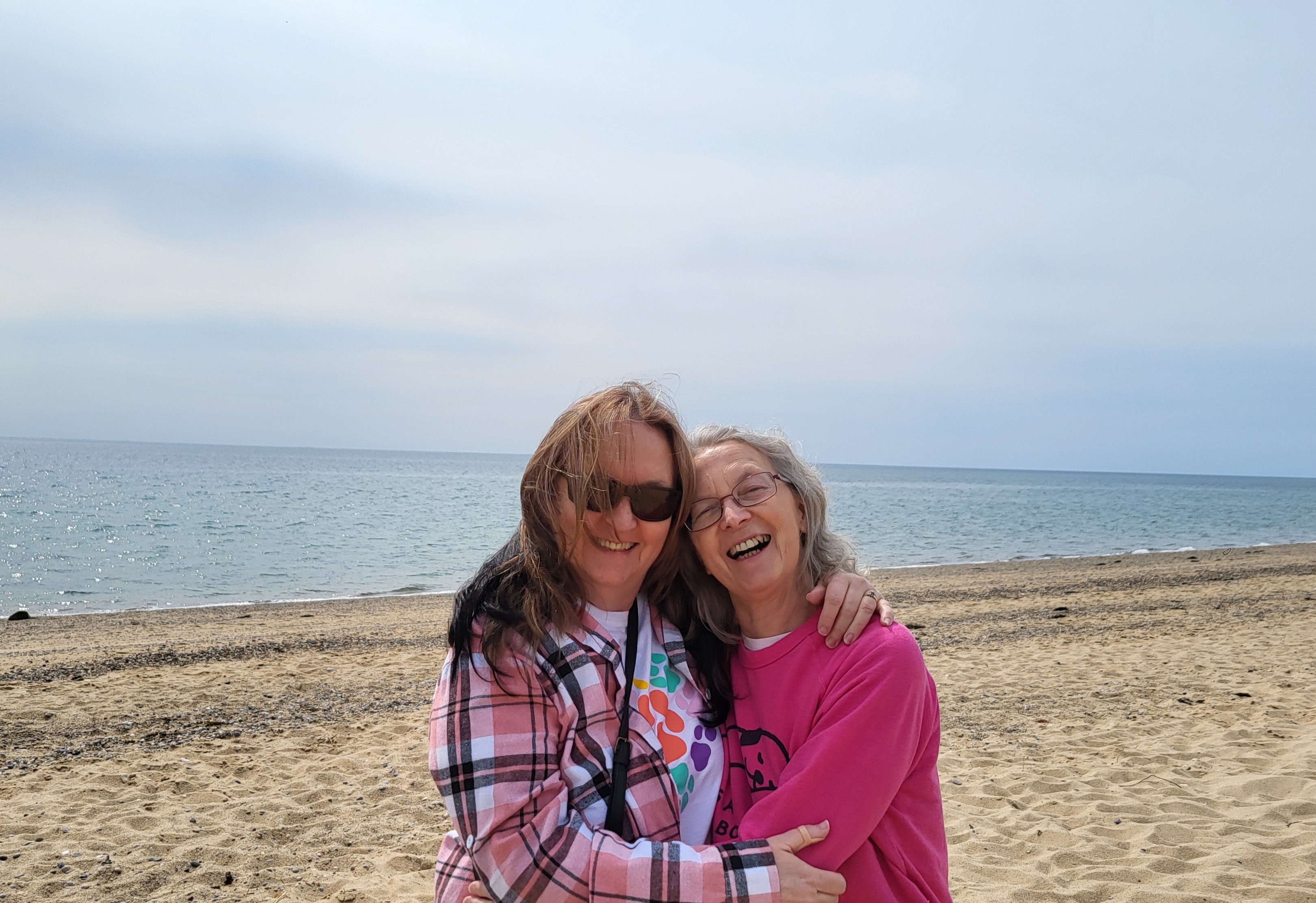 Two friends laughing together on the beach in Provincetown